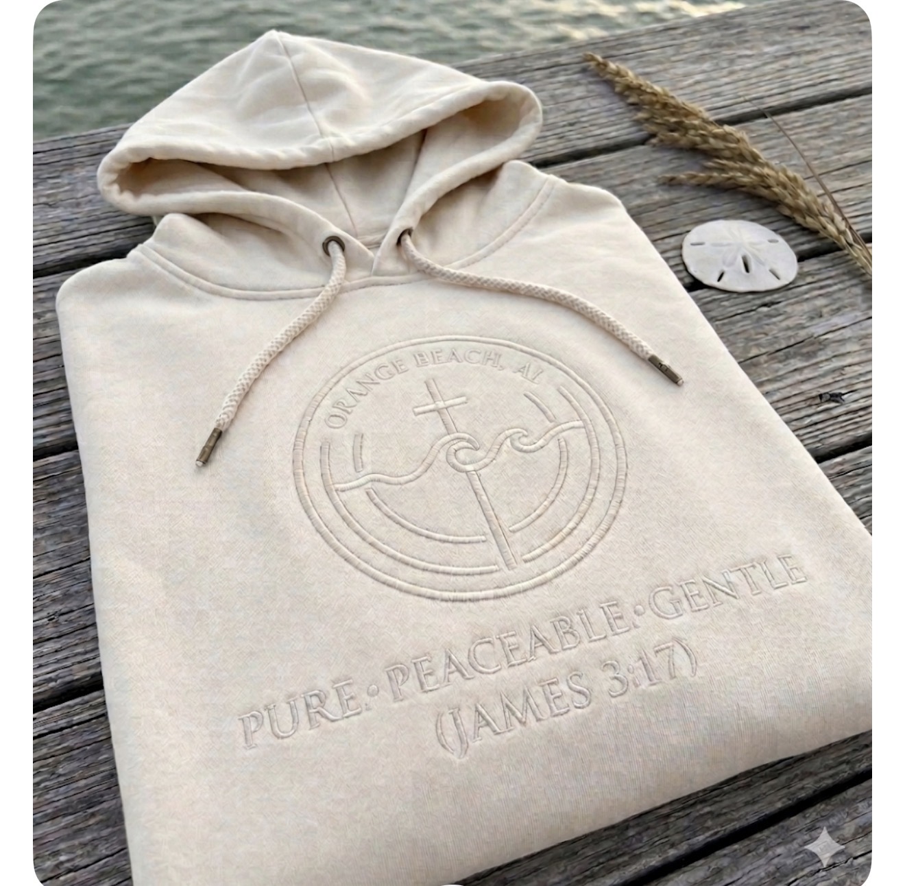 Sand-colored Orange Beach hoodie with tonal embroidered emblem on a weathered dock