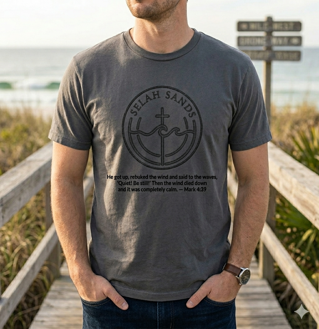 Man in washed charcoal Selah Sands tee on a coastal boardwalk with Mark 4:39 print